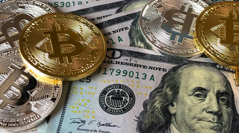 A close-up photo depicting Bitcoin coins on top of US dollar bills, symbolizing finance and cryptocurrency.